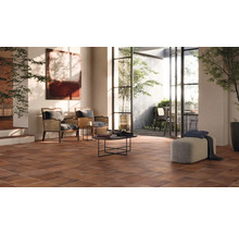 Wohnzimmer mit braunen Bodenfliesen, Sitzgelegenheiten und Zugang zum Außenbereich.