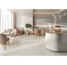 Innenansicht eines Cafés mit Tischen, Stühlen, einer Theke und einem Terrazzoboden.