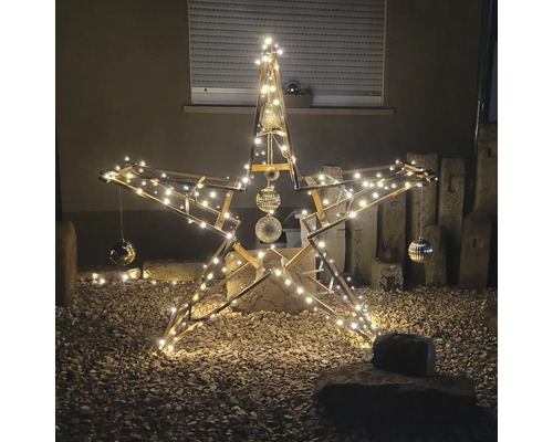 Dekorativer Holzstern mit Beleuchtung und Kugeln im Garten.