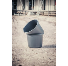 Zwei Mörtelkübel aus Kunststoff stehen übereinander auf einer Baustelle.