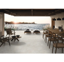 Terrasse mit Sitzmöbeln, Liegen und Esstisch mit Meerblick.