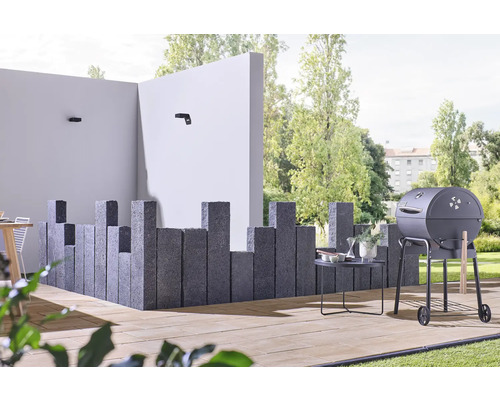Außenbereich mit Grill, Steinsäulen und Gartenmöbeln auf einer Terrasse