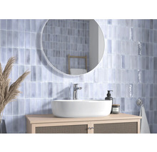 Badezimmer mit Waschbecken, Spiegel und hellblauen Fliesen