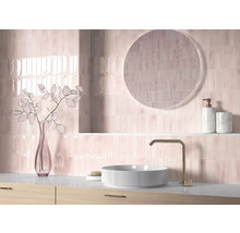 Badezimmer mit rosa Fliesen, rundem Spiegel, Waschbecken und Armatur.