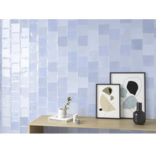 Wandgestaltung mit hellblauen, rechteckigen Fliesen und dekorativen Elementen auf einem Holztisch