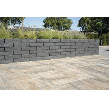 Mauer aus grauen Mauersteinen und Pflastersteinen im Garten