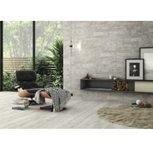 Heller Wohnraum mit Wand- und Bodenfliesen in Steinoptik, Sessel und Dekorationen.