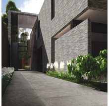 Modernes Haus mit grauer Steinfassade und gepflasterter Auffahrt.