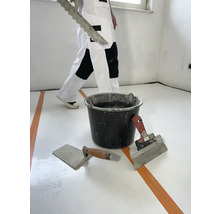 Raumrenovierung mit Spachtel, Glättkelle und Eimer Mörtel