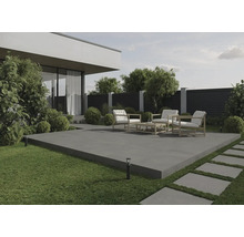 Terrasse mit Gartenmöbeln auf Betonplatten, umgeben von Rasen und Pflanzen.