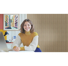 Frau lächelt an einem Schreibtisch vor einer Wand aus Holzpaneelen.