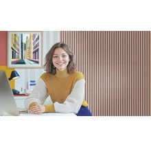 Frau sitzt an einem Schreibtisch vor einer Akustikpaneel-Wand im Arbeitszimmer