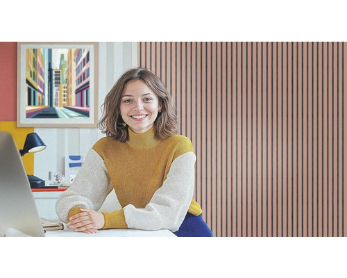 Frau sitzt an einem Schreibtisch vor einer Akustikpaneel-Wand im Arbeitszimmer