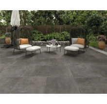 Terrasse mit Bodenplatten, Sitzgruppe und Sonnenschirm im Garten.