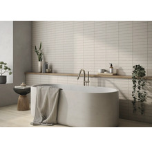 Badezimmer mit Badewanne, Armatur, Handtuch, Ablage und Wandfliesen