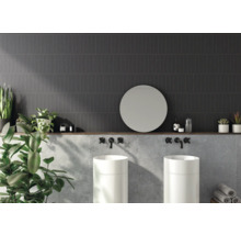 Badezimmer mit dunklen Wandfliesen, zwei Waschbecken, rundem Spiegel und Dekoration