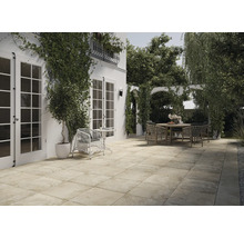 Terrasse mit Steinfliesen, Gartenmöbeln und üppigem Grün