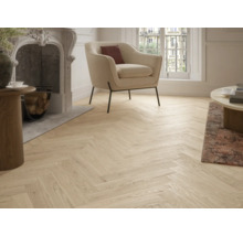 Wohnzimmer mit Kamin, Sessel und hellem Parkettboden im Fischgrätmuster