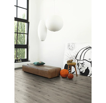 Heller Raum mit grauer Laminatboden, brauner Sitzbank, Kunstwerk und großen Fenstern für eine freundliche Atmosphäre