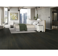 Schlafzimmer mit dunklem Holzboden, Bett und weißem Sessel