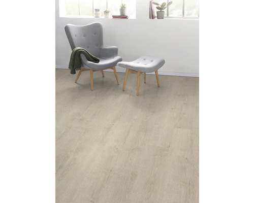 Heller Laminatboden in einem Wohnraum mit Sessel und Fußhocker.