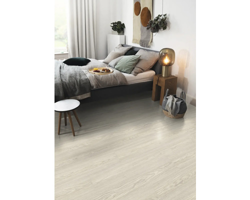 Ein helles Schlafzimmer mit Holzboden, Bett und Beistelltisch.