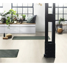 Heller Raum mit Yogamatten, Kissen, Zimmerpflanzen und Fenstern