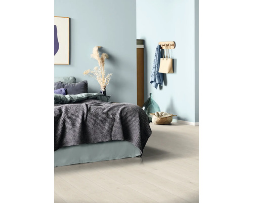 Helles Schlafzimmer mit Bett, Textilien, Wandhaken und Dekoration