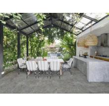 Essbereich im Freien mit Steinfliesenboden, Tisch und Stühlen unter einem begrünten Glasdach