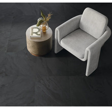 Raumansicht mit dunklen Fliesen, Sessel und Beistelltisch