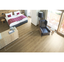 Heller Raum mit Bett, Sessel und verlegtem Laminatboden