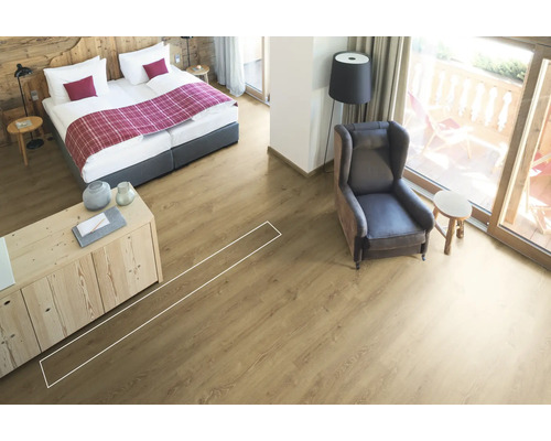 Heller Raum mit Bett, Sessel und verlegtem Laminatboden