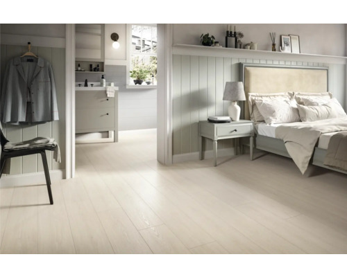 Helles Schlafzimmer mit Holzboden, Bett und Badezimmer im Hintergrund