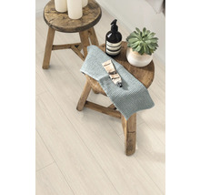 Szene mit Hocker, Handtuch, Kosmetikprodukten und Zimmerpflanze auf einem Laminatboden