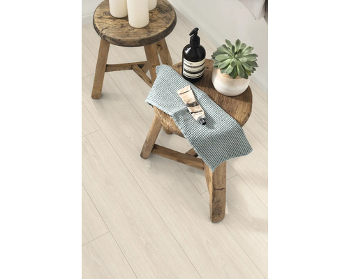 Szene mit Hocker, Handtuch, Kosmetikprodukten und Zimmerpflanze auf einem Laminatboden
