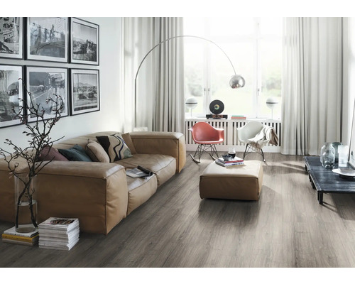 Heller Wohnraum mit Sofa, Sesseln, Stehlampe und grauem Holzboden