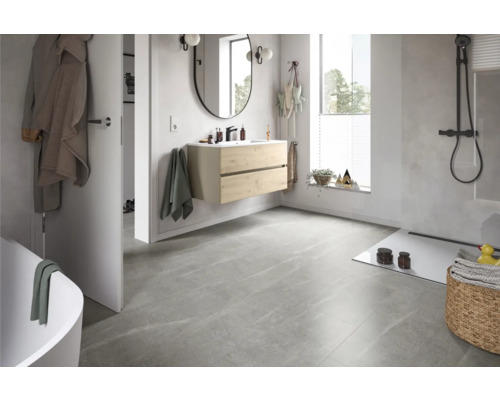 Helles Badezimmer mit Waschtisch, Spiegel, Dusche und grauen Bodenfliesen.