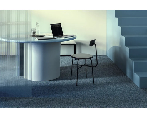 Szene mit rundem Tisch, Laptop, Stuhl und Treppe in einem modernen Büro.