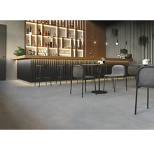 Innenraum mit Bar, Barhockern, Tischen und Stühlen auf Fliesenboden.