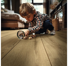 Kind spielt mit Walnüssen auf einem Holzboden im Wohnzimmer