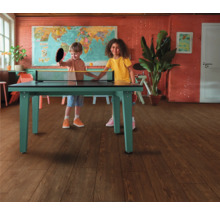 Zwei Kinder spielen Tischtennis im Innenraum auf einem grünen Tischtennistisch.