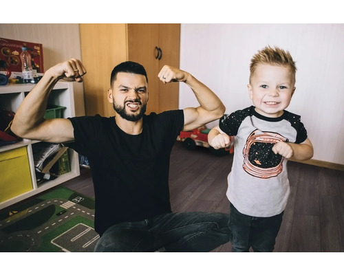 Vater und Sohn zeigen Muskeln im Kinderzimmer