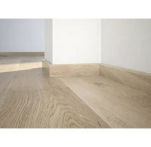 Nahaufnahme von Laminatboden mit passenden Sockelleisten entlang einer weißen Wand