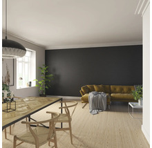 Helles Wohnzimmer mit Holzboden, Esstisch, Stühlen und Sofa vor einer dunklen Wand