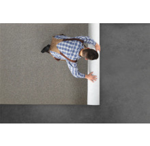 Mann verlegt Teppichboden in einem Raum.