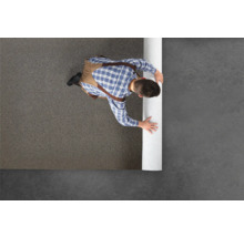 Mann rollt Teppich auf dem Boden aus