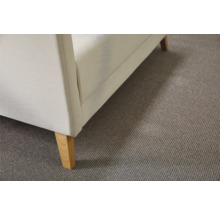 Detailansicht eines weißen Sofas mit Holzfüßen auf einem grauen Teppich