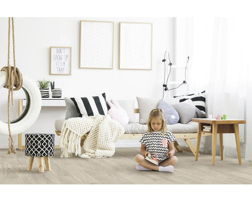 Kinderzimmer mit hellem Laminatboden, Sofa, Reifenschaukel und spielendem Mädchen