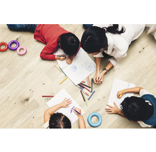Kinder malen auf einem Holzboden mit Stiften auf Papier.