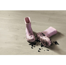 Paar schmutzige Kindergummistiefel auf einem Holzboden